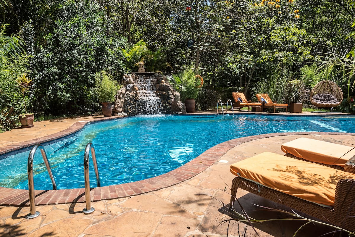 Heated pool with waterfall wrapped in tropical greenery